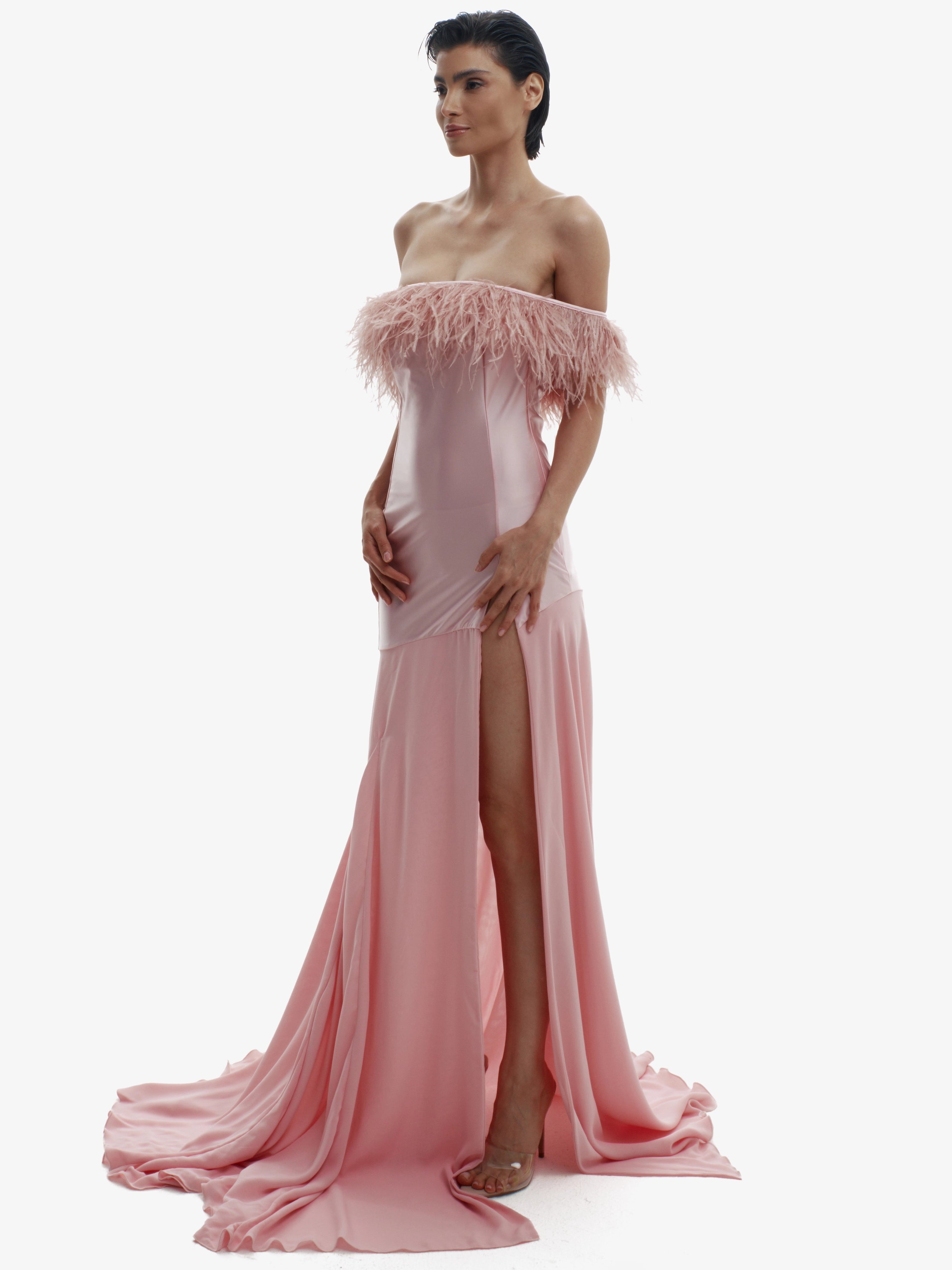 Woman wearing a pink evening gown with feathered top on a white background