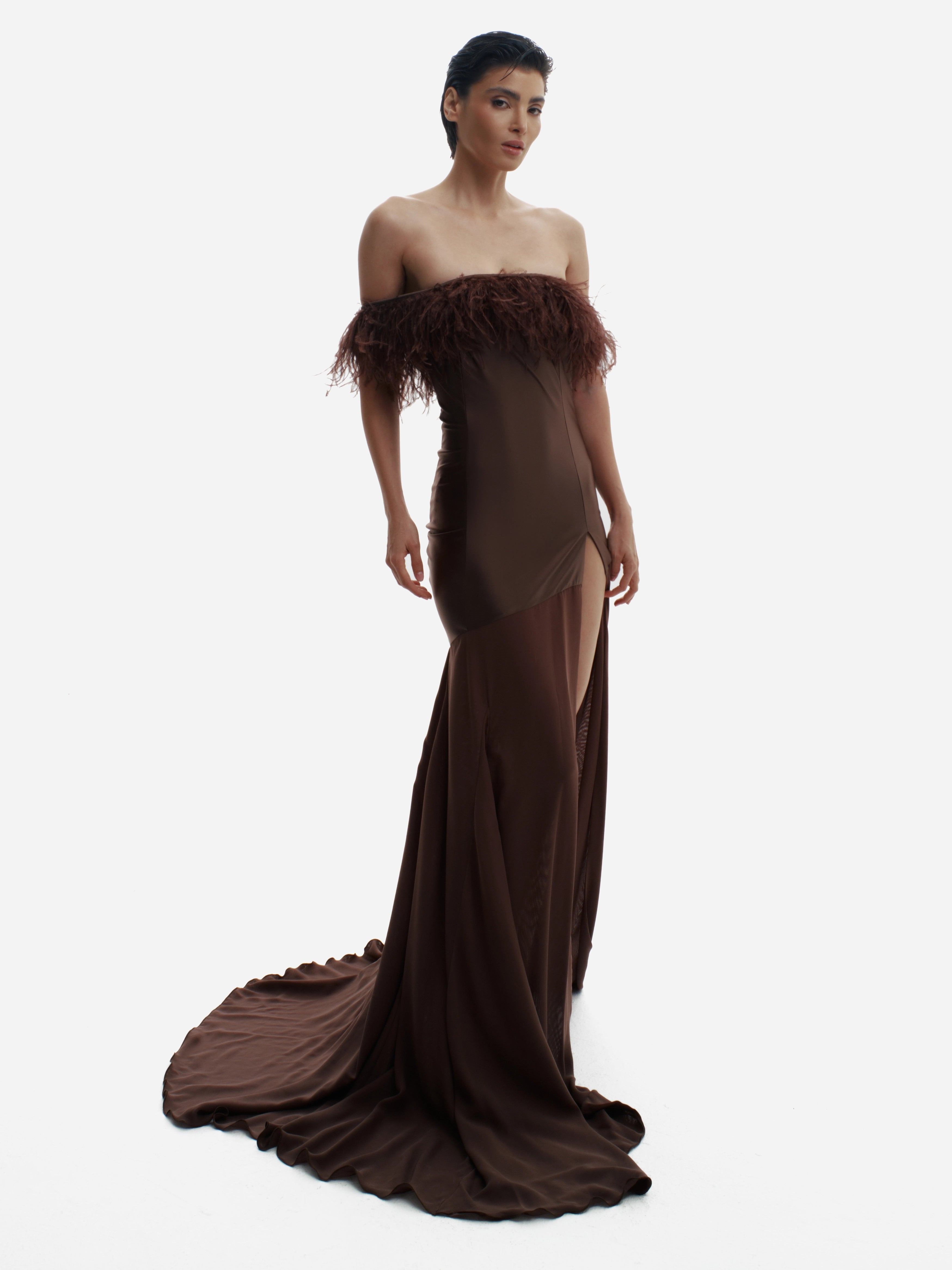 Woman wearing a brown strapless gown with feathered details on a white background