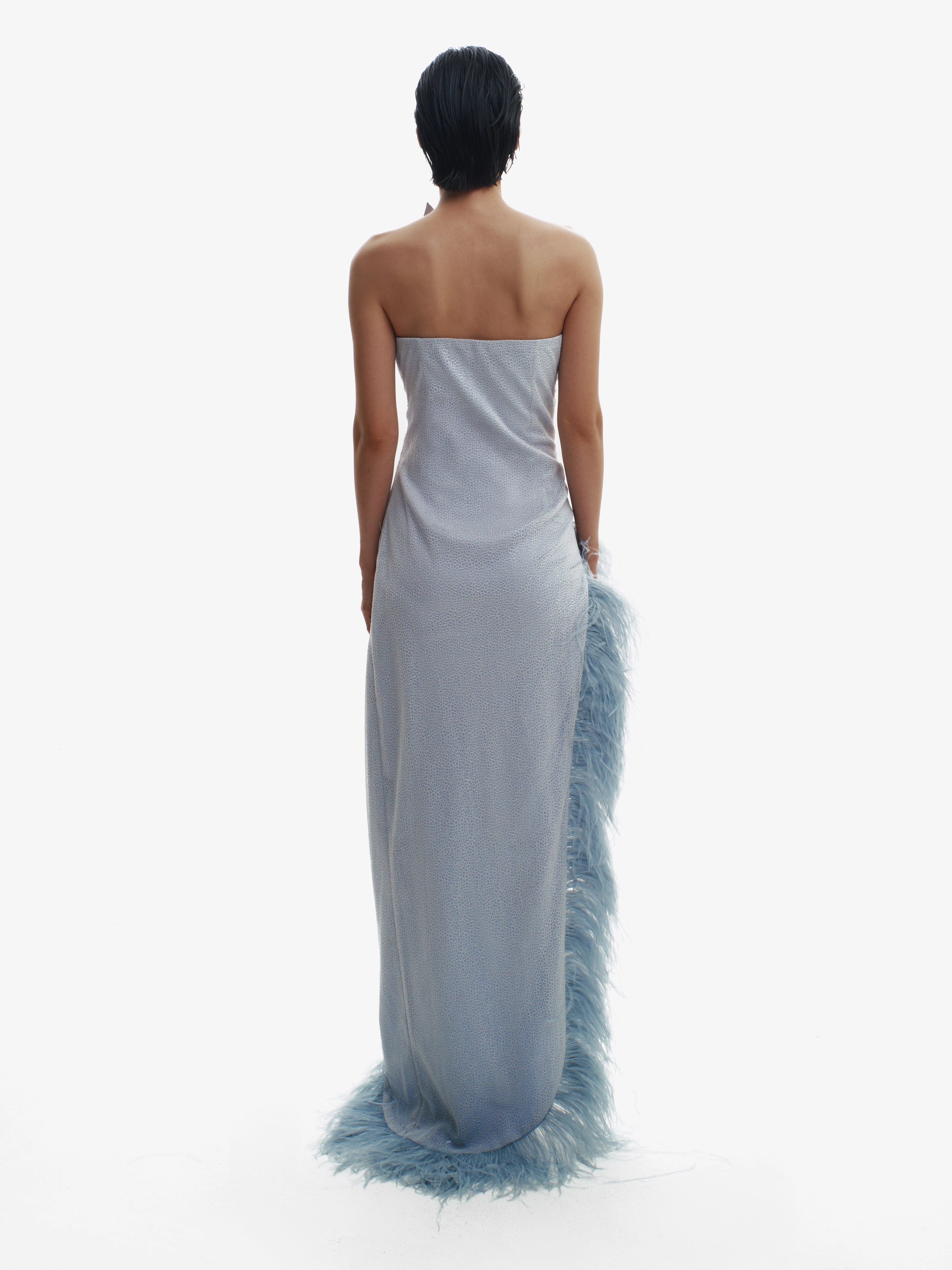 Woman wearing a strapless gown with feather details on a white background