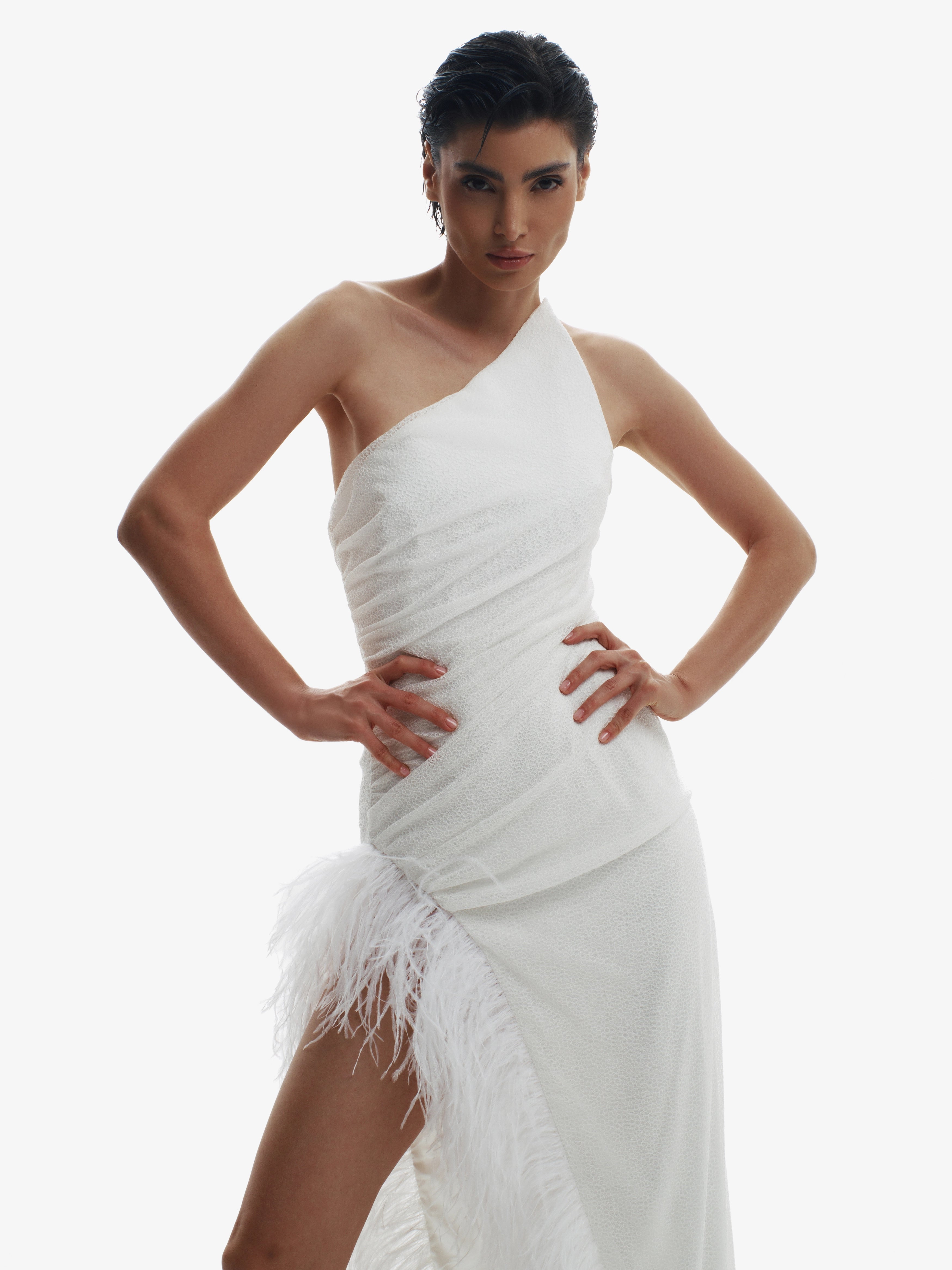 Woman wearing a white one-shoulder dress with feather details on a white background