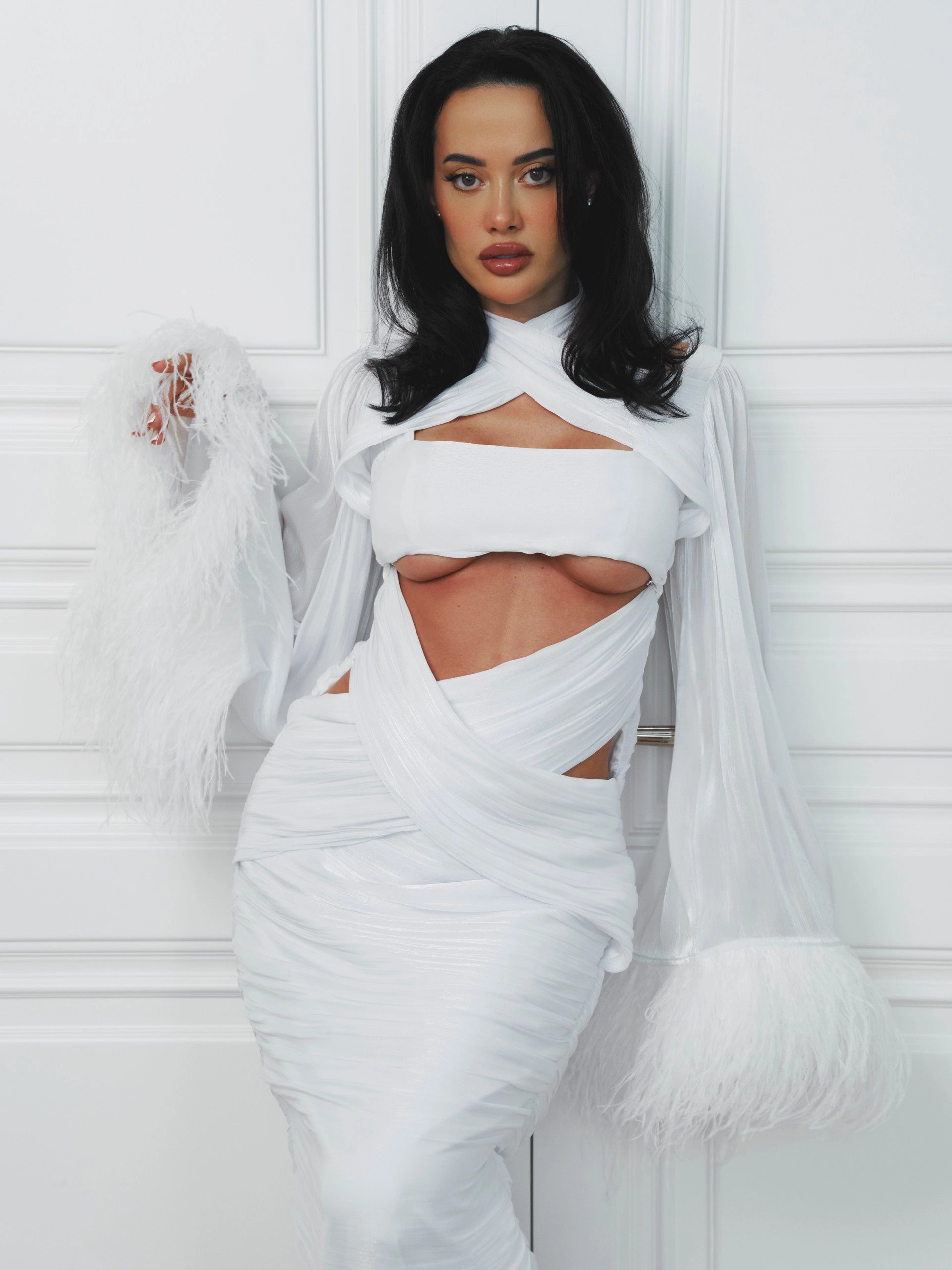 Woman wearing a white dress with cut-out design against a white background