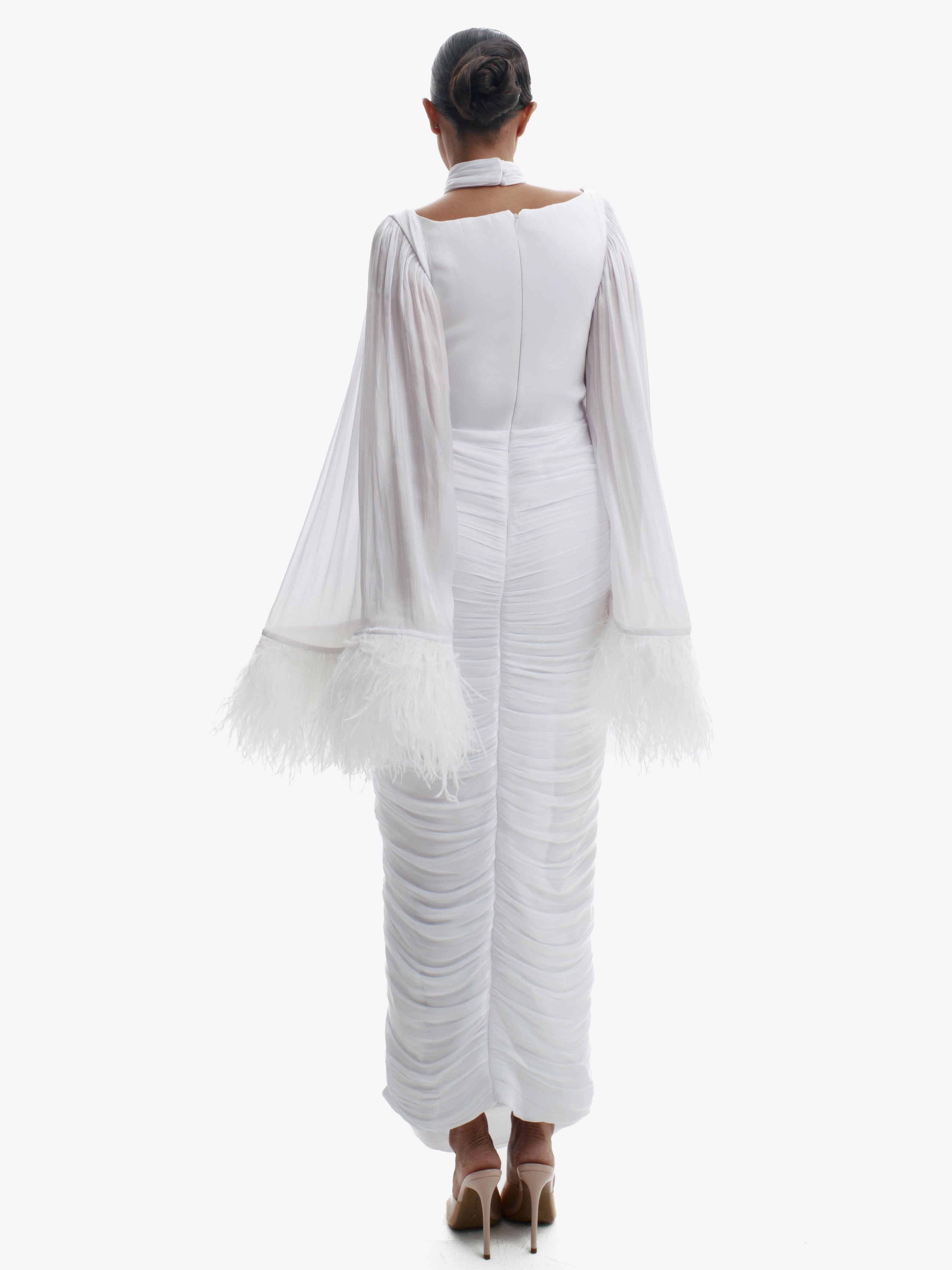 Woman wearing a white outfit with ruffled sleeves and bottom on a white background