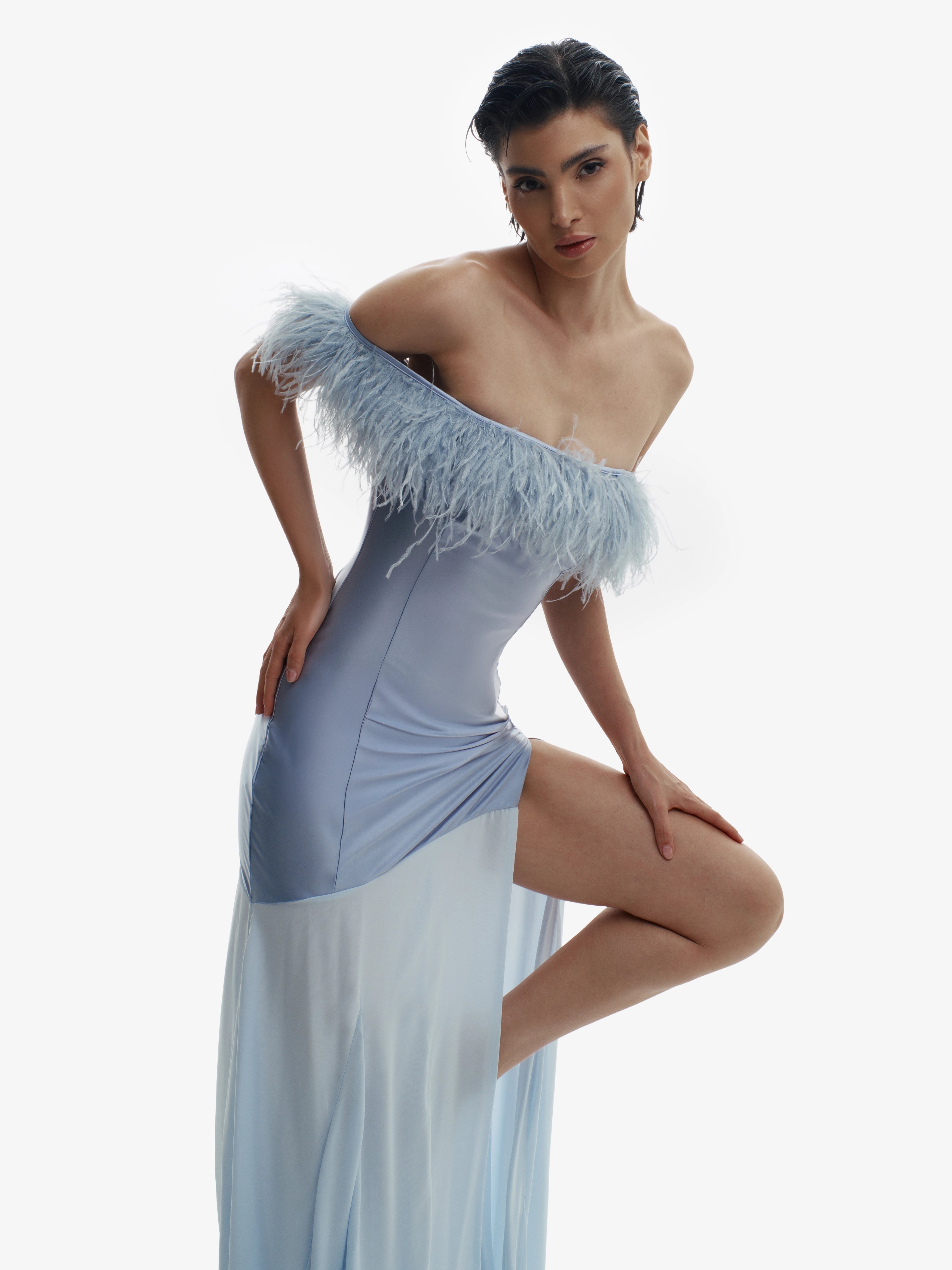 Woman wearing a light blue off-shoulder dress with feather details on a white background