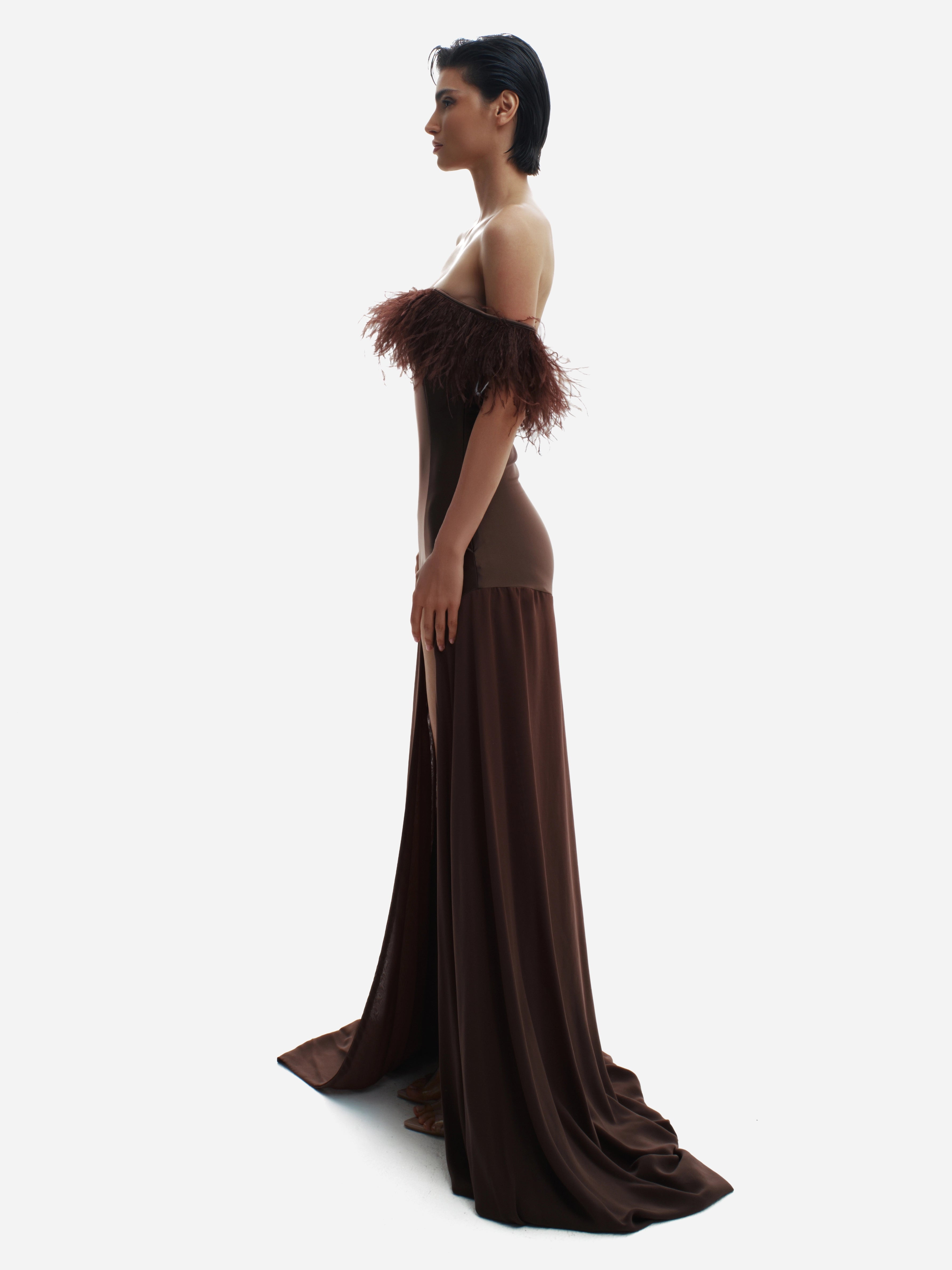 Woman wearing a brown evening gown with feathered shoulders on a white background