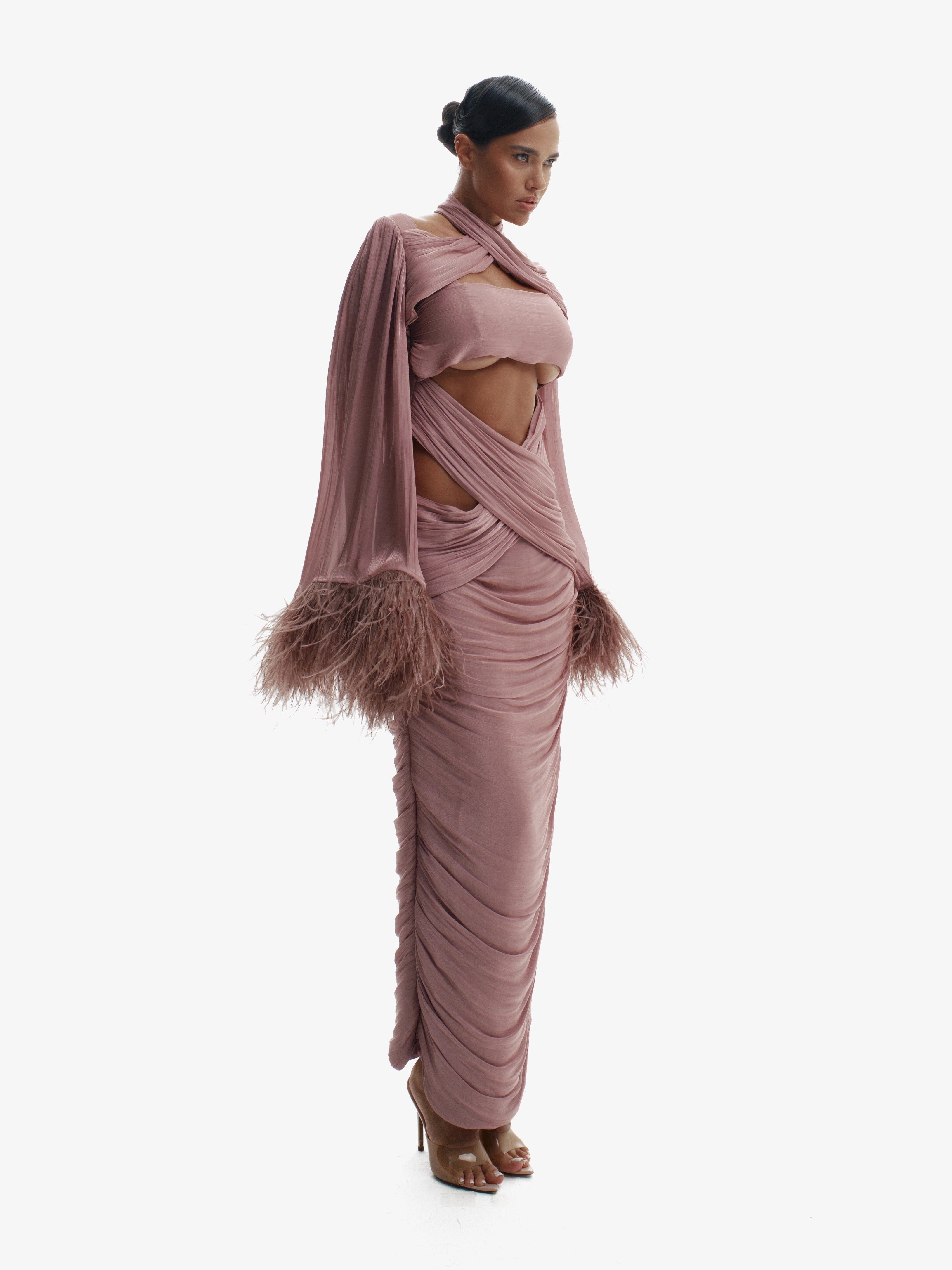 Woman wearing a pink gown with feathered details on a white background
